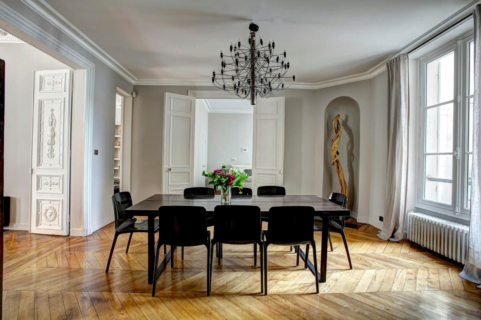 Salle à manger d'un appartement haussmannien : moulures, parquet en chevrons et lustre