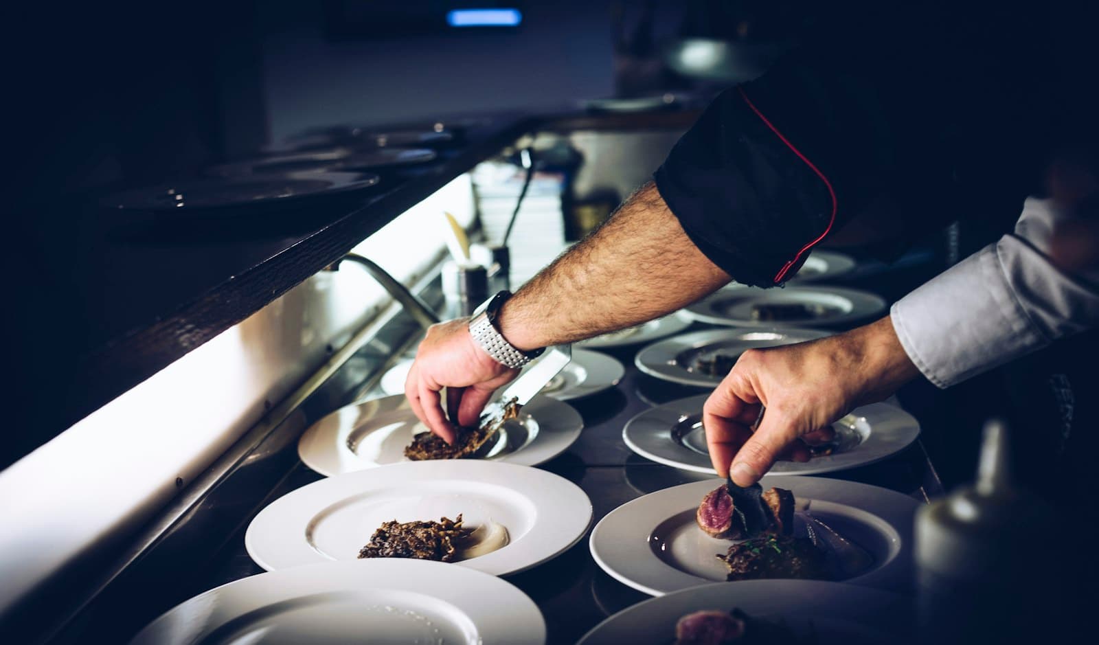 Mains d'un chef dressant des assiettes en cuisine