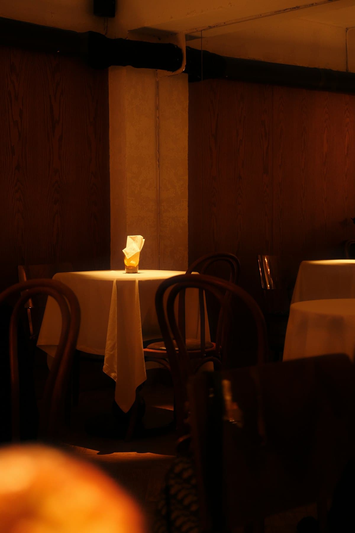 Table nappée de blanc dans une salle de restaurant boisée, sous une lumière chaude du soir