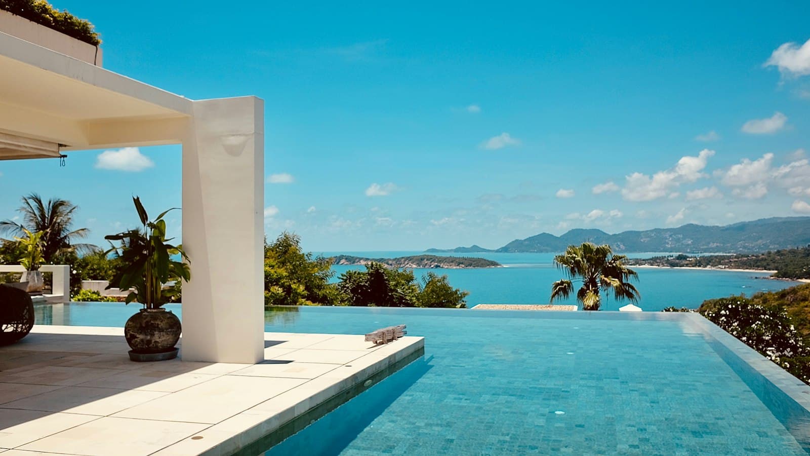 Piscine à débordement d'une villa surplombant une baie bleue